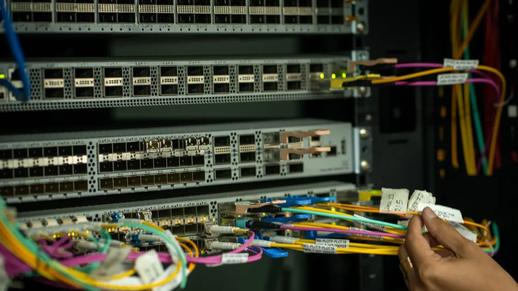 Manos trabajando con cableado de fibra óptica en una infraestructura de red
