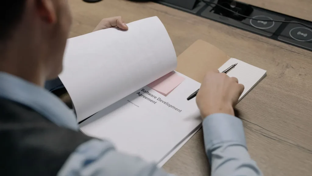 Profesional revisando documentación de un acuerdo de desarrollo de software y contratación tecnológica